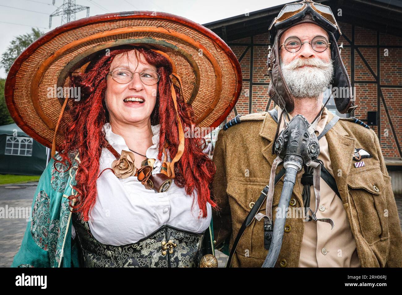 Henrichenburg, Waltrop, Germany. 12th Aug, 2023. Two participants have come well prepared for the rain. Steampunk fans, groups in costumes and visitors, many in retro-futuristic or Victorian inspired outfits, have fun despite the heavy rain showers on day one of the Steampunk Jubilee Festival weekend at the historic Henrichenburg boat lift, a listed architectural landmark and industrial heritage site. Credit: Imageplotter/Alamy Live News Stock Photo