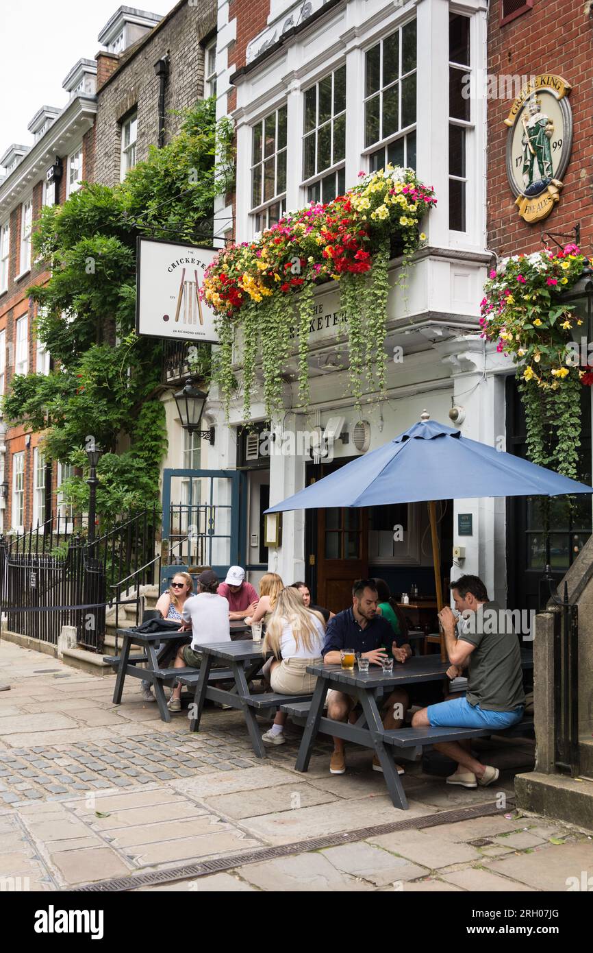 People sitting and having a drink outside the Cricketers public house on Richmond Green, Richmond, TW9, Surrey, England, U.K. Stock Photo