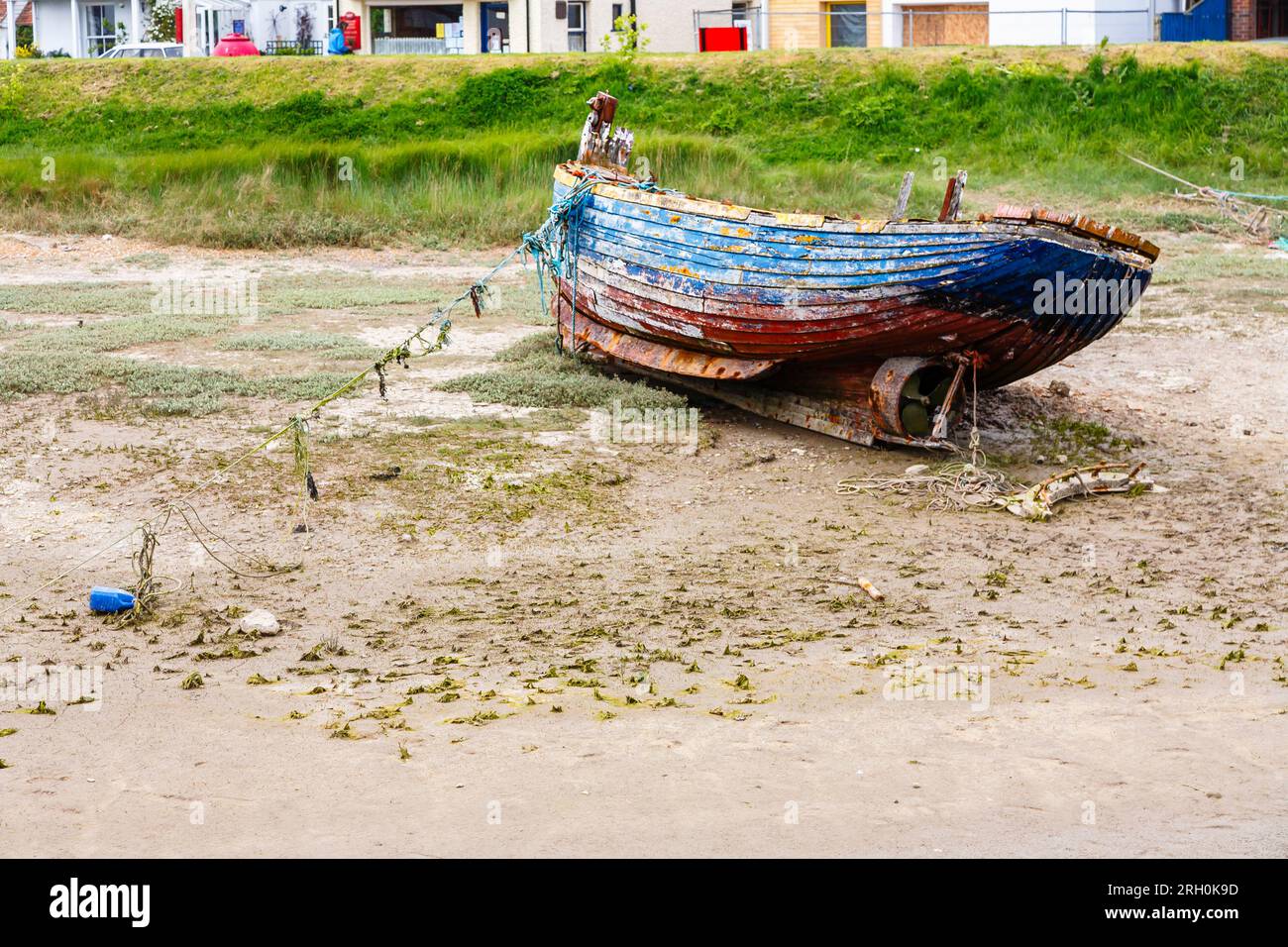 An old dilapidated wooden boat grounded at low tide on the banks of the River Rother in Rye Harbour, a small East Sussex coast village near Rye town Stock Photo