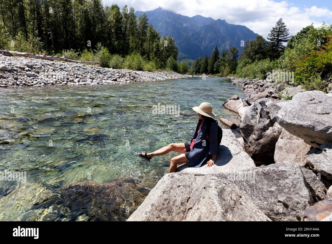 Mature woman kicking her feet into the cool river water during a summer
