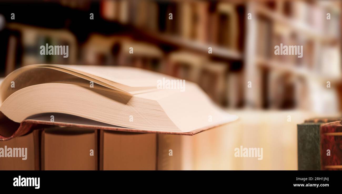 An open book on the bookshelf background in interior, close-up. Stock Photo