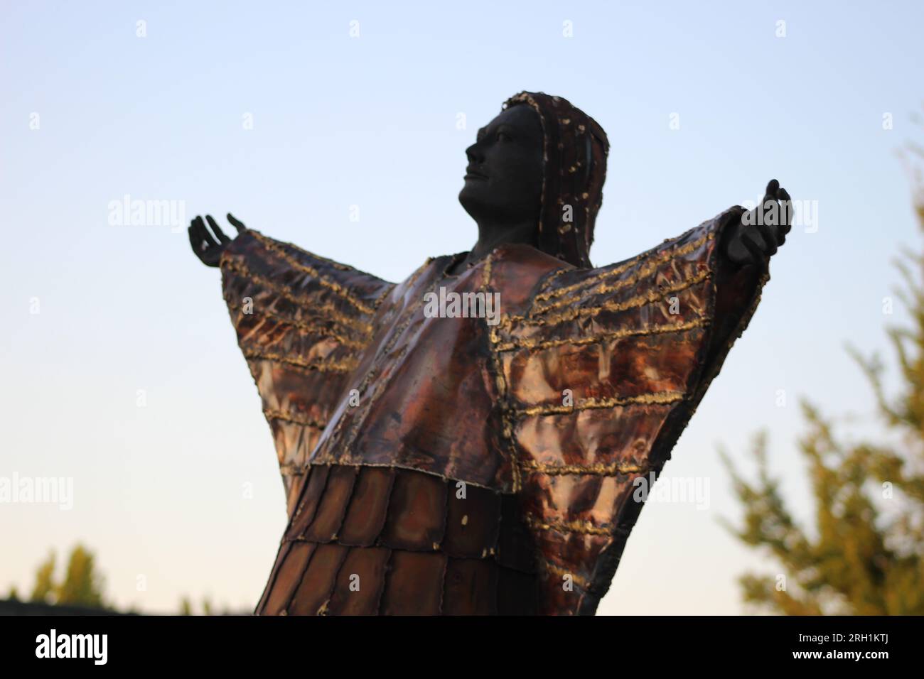 'A brilliant bronze testament, capturing the unwavering spirit and ancestral grace of a native woman, hands outstretched to the heavens' Stock Photo