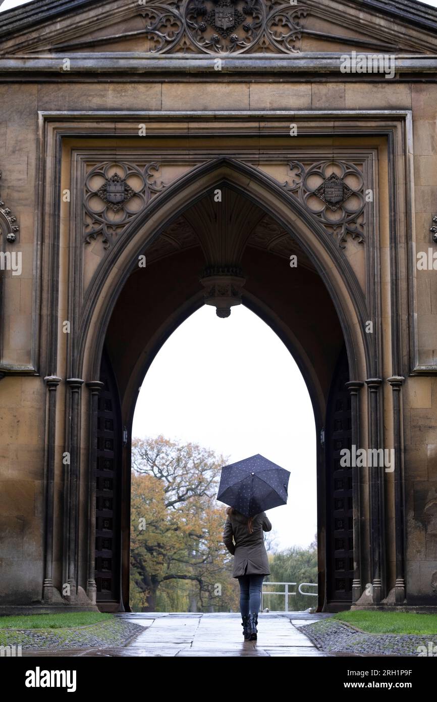 Woman under umbrella walking in the streets of Cambridge Stock Photo