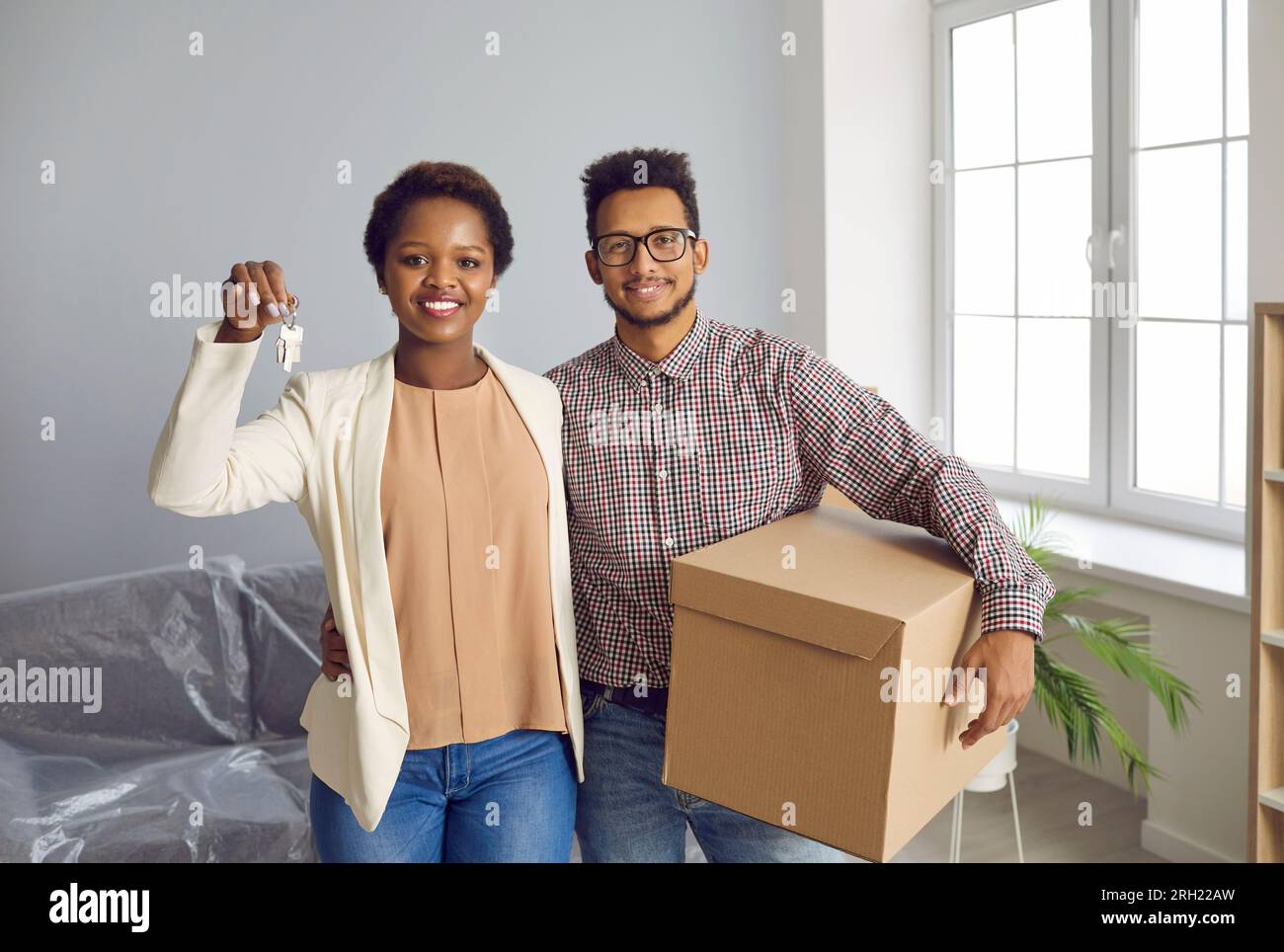 Happy ethnic couple show keys moving to new house Stock Photo - Alamy