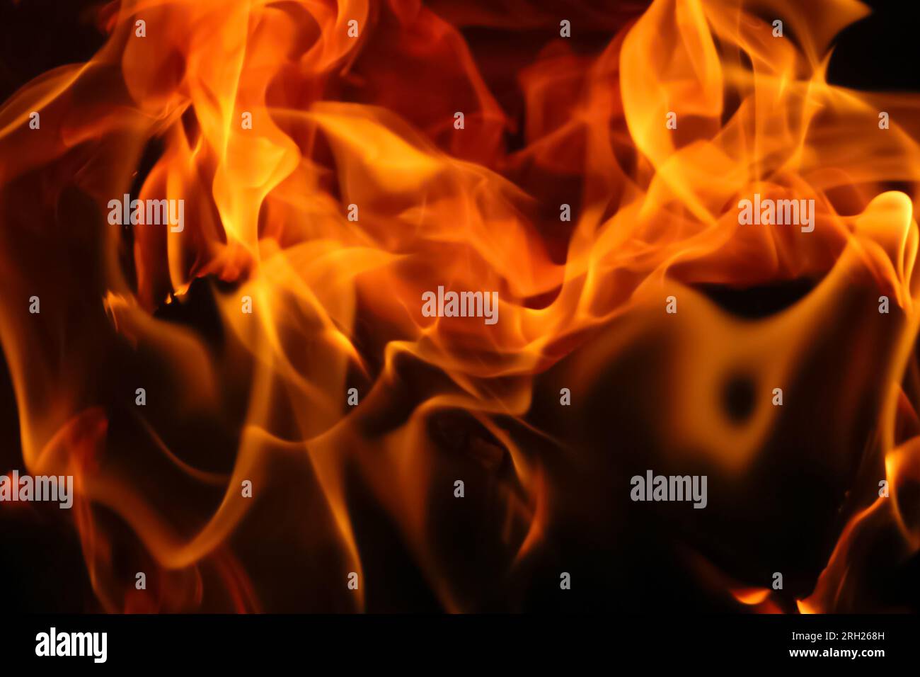 Fiery flames on a dark backdrop create a captivating abstract texture ...