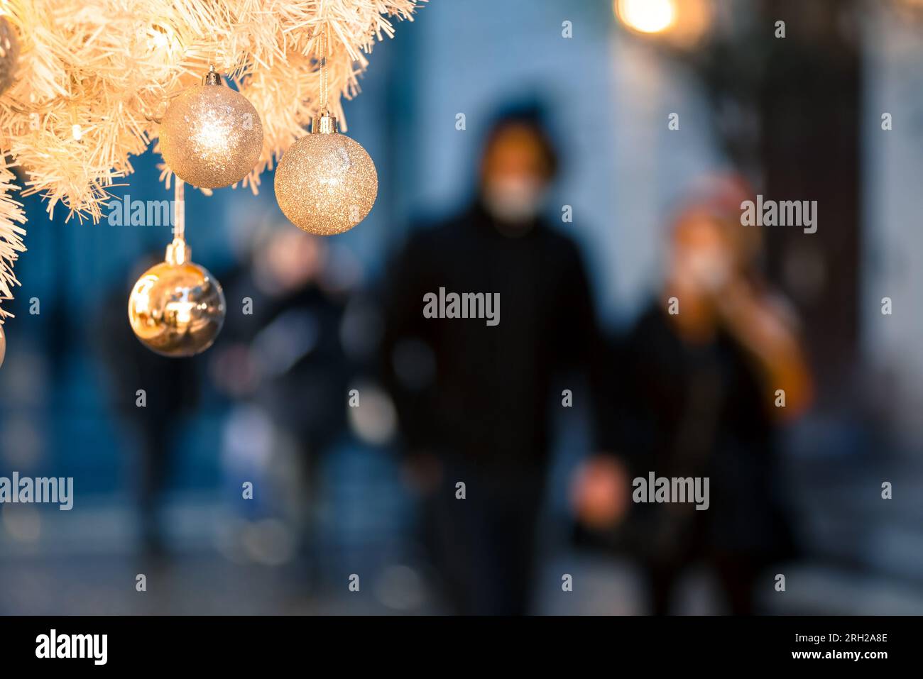 Defocused people passing by decorated Christmas Tree on the street Stock Photo