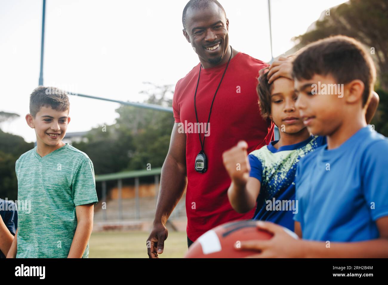 Coach training an elementary school football team. Sports instructor having a practice session with a group of children in primary school. Student men Stock Photo