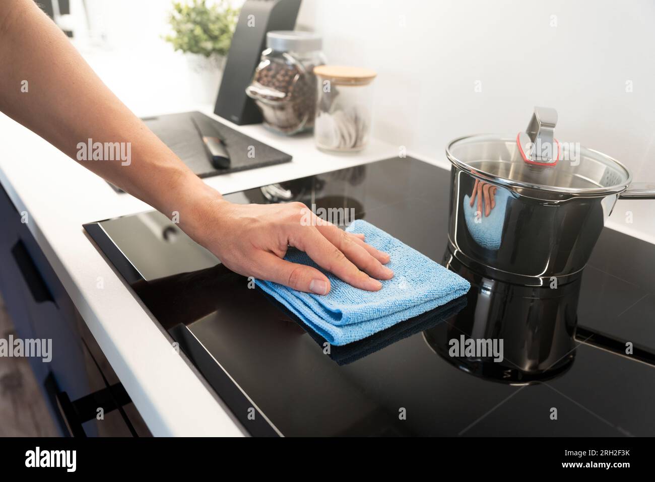 Woman cleaning induction stove. Modern kitchen with induction hob Stock
