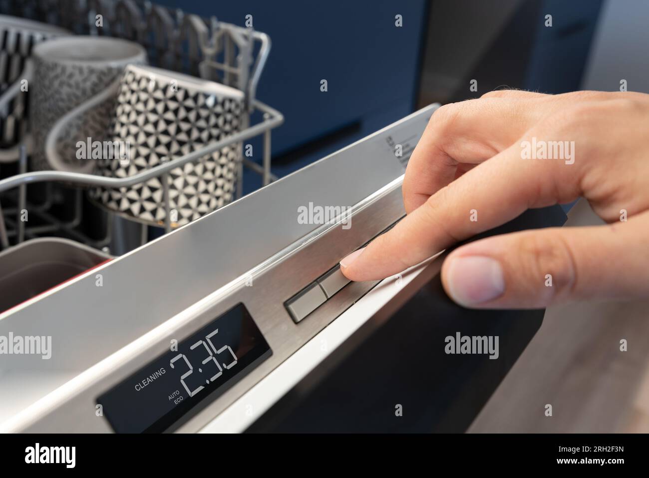 Man pushing start button on the control panel of the dishwasher Stock