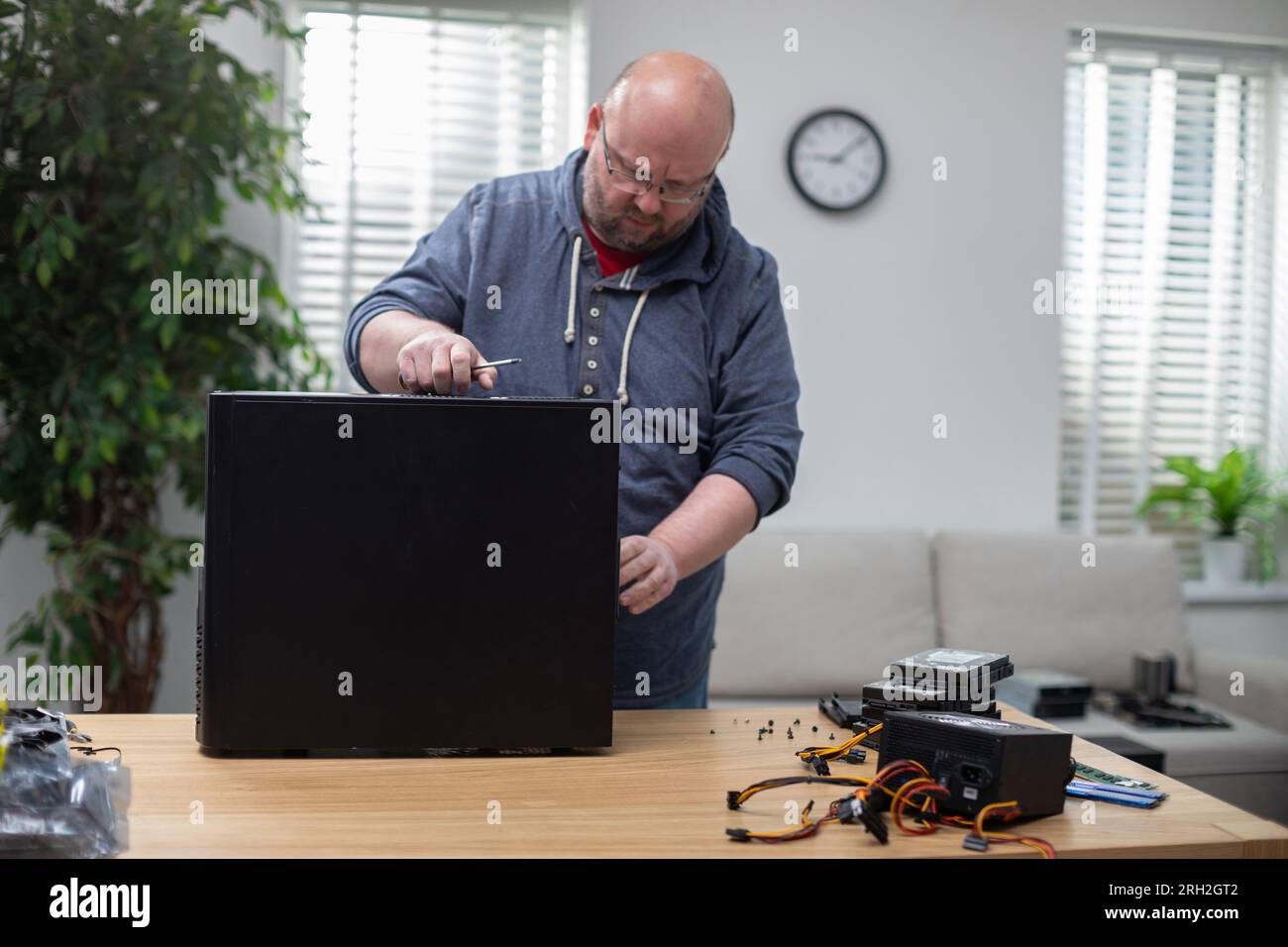 IT specialist repairs desktop computer that stands on desk Stock Photo