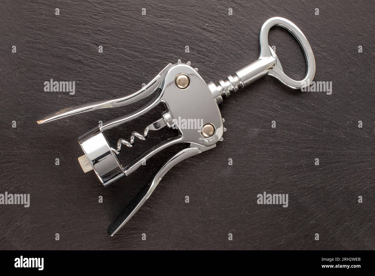 One stainless steel corkscrew on slate stone, macro, top view. Stock Photo