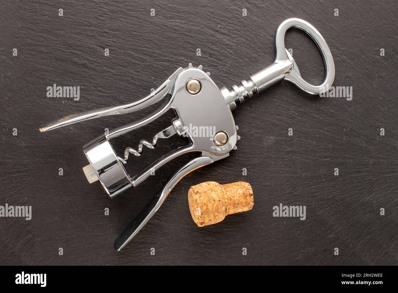 One stainless steel corkscrew with stopper on slate stone, macro, top view. Stock Photo
