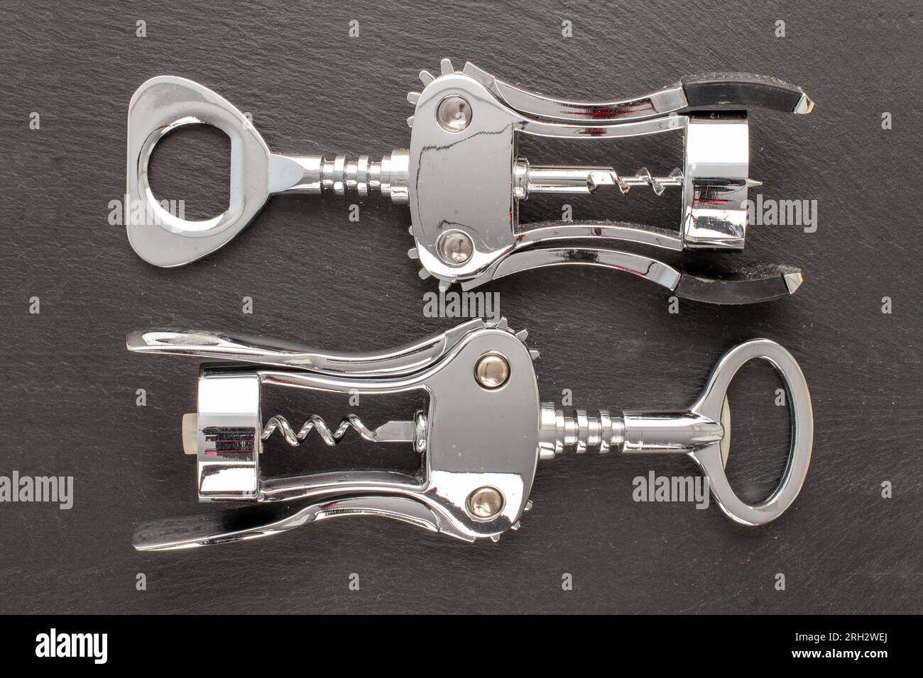 Two stainless steel corkscrews on slate stone, macro, top view. Stock Photo