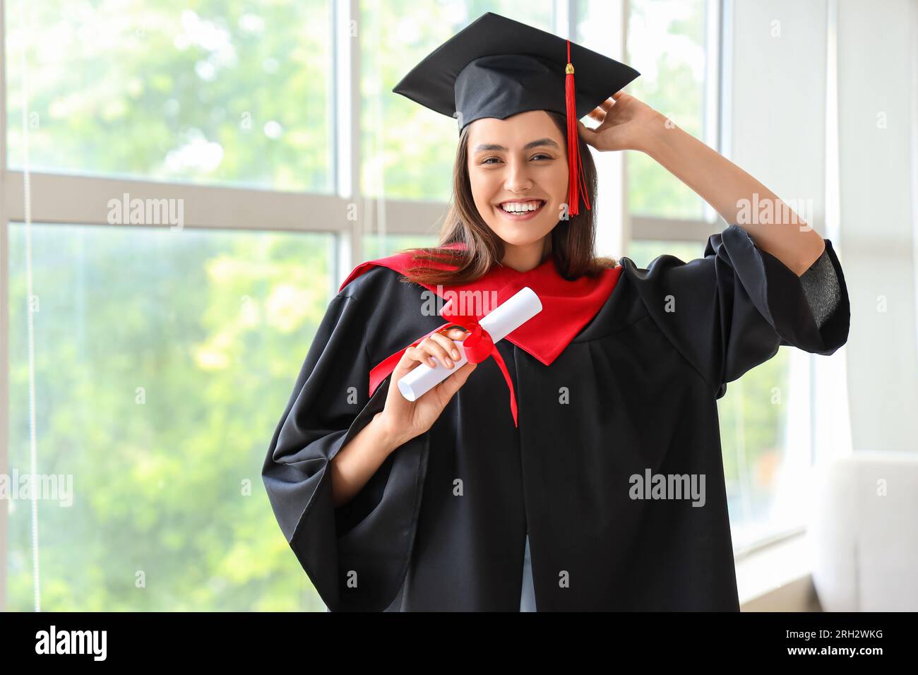 Female graduate student with diploma near window in room Stock Photo ...