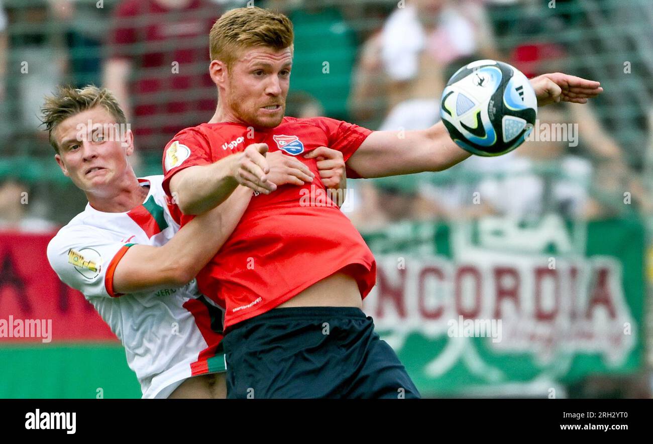 Unterhaching, Germany. 13th Aug, 2023. Soccer: DFB Cup, SpVgg Unterhaching - FC Augsburg, 1st round at Sportpark Unterhaching. Mathias Fetsch (r) of Unterhaching and Frederik Winther of Augsburg fight for the ball. Credit: Sven Hoppe/dpa - IMPORTANT NOTE: In accordance with the requirements of the DFL Deutsche Fußball Liga and the DFB Deutscher Fußball-Bund, it is prohibited to use or have used photographs taken in the stadium and/or of the match in the form of sequence pictures and/or video-like photo series./dpa/Alamy Live News Stock Photo