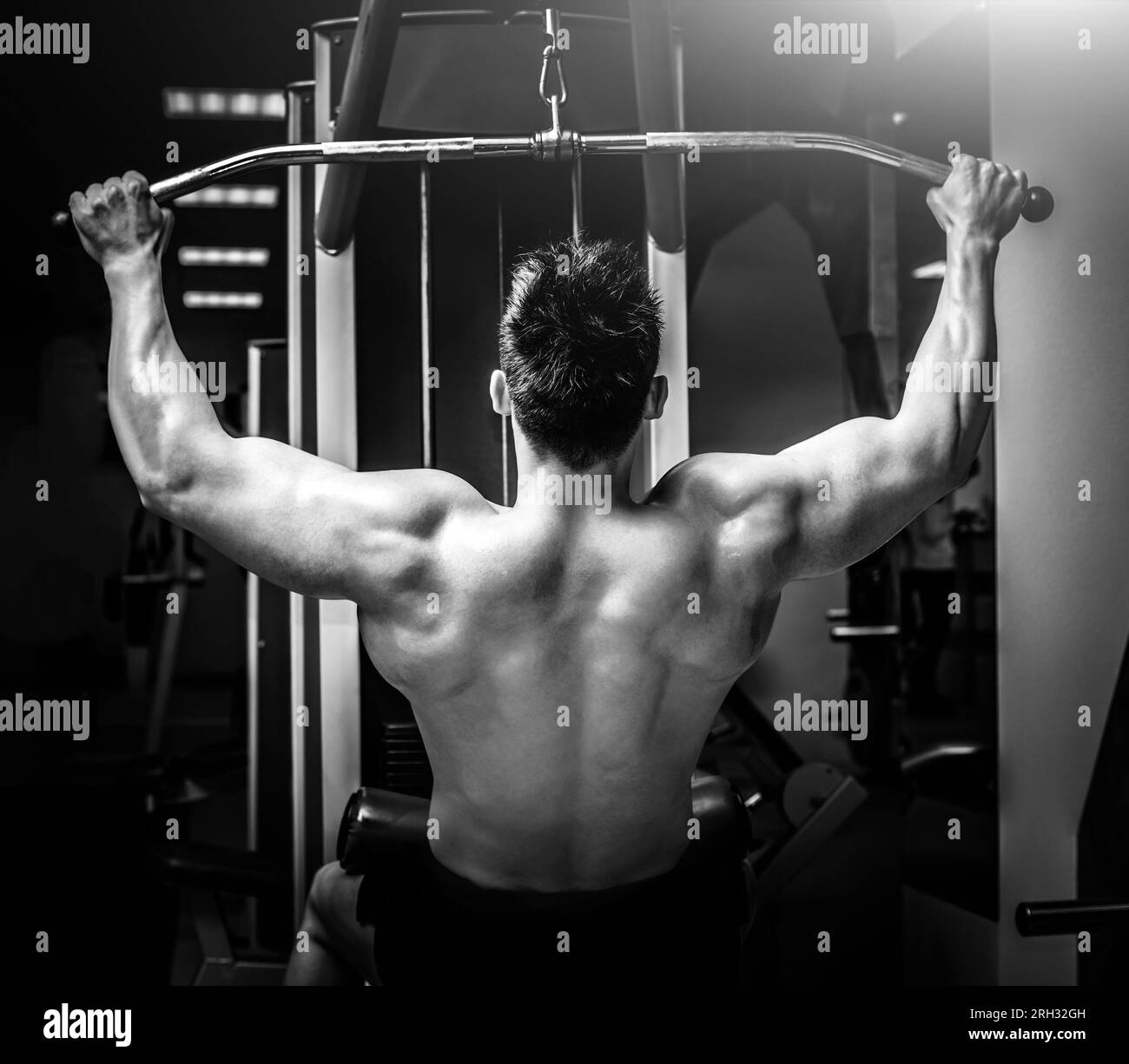 Strong man pulling a vertical upper block doing back exercises in