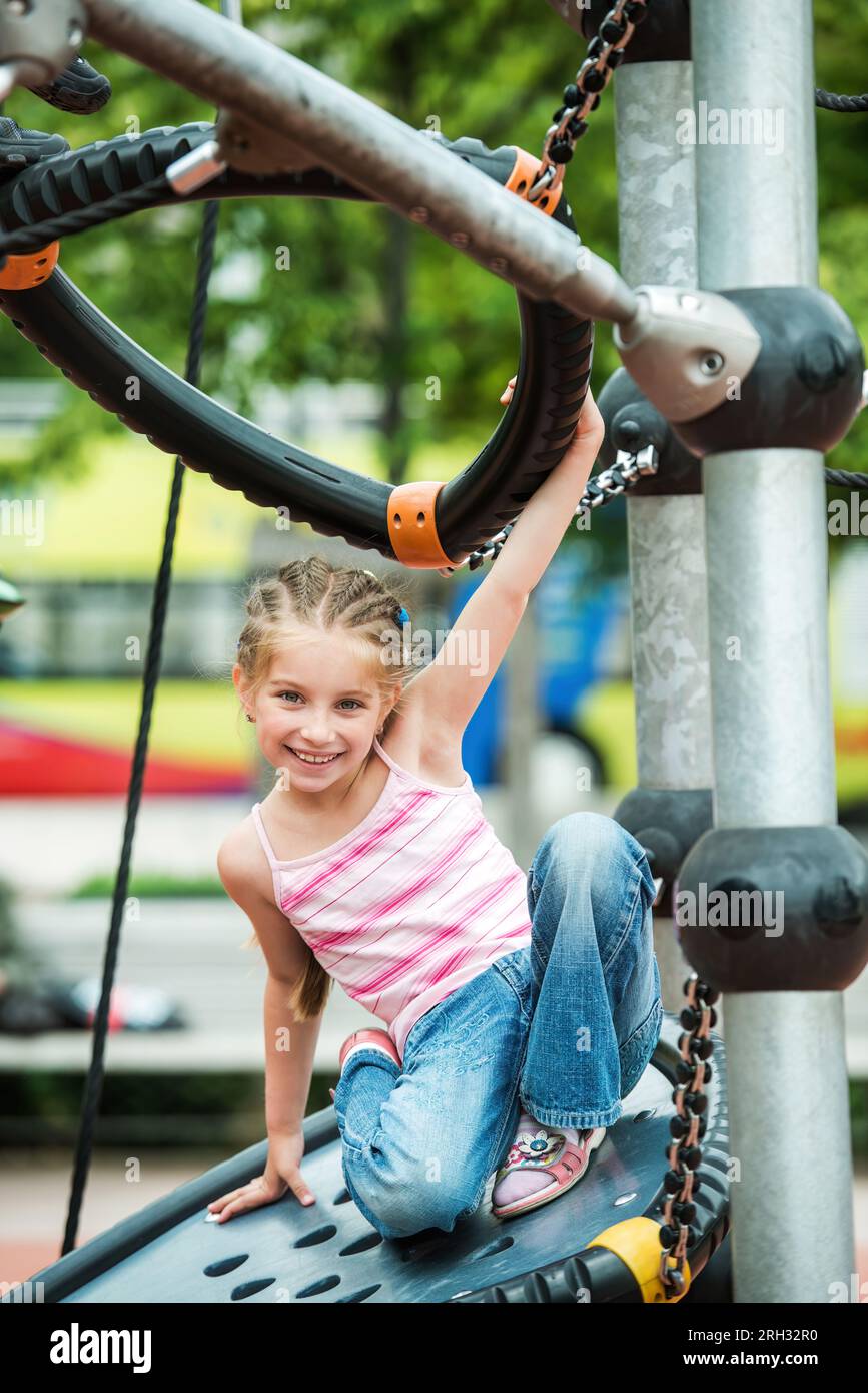 Happy cute and smiling little girl playing at the playground outdoor ...