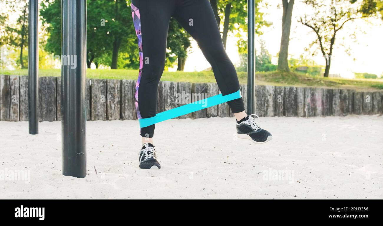 Fitness girl doing workout legs exercises with rubber elastic strap
