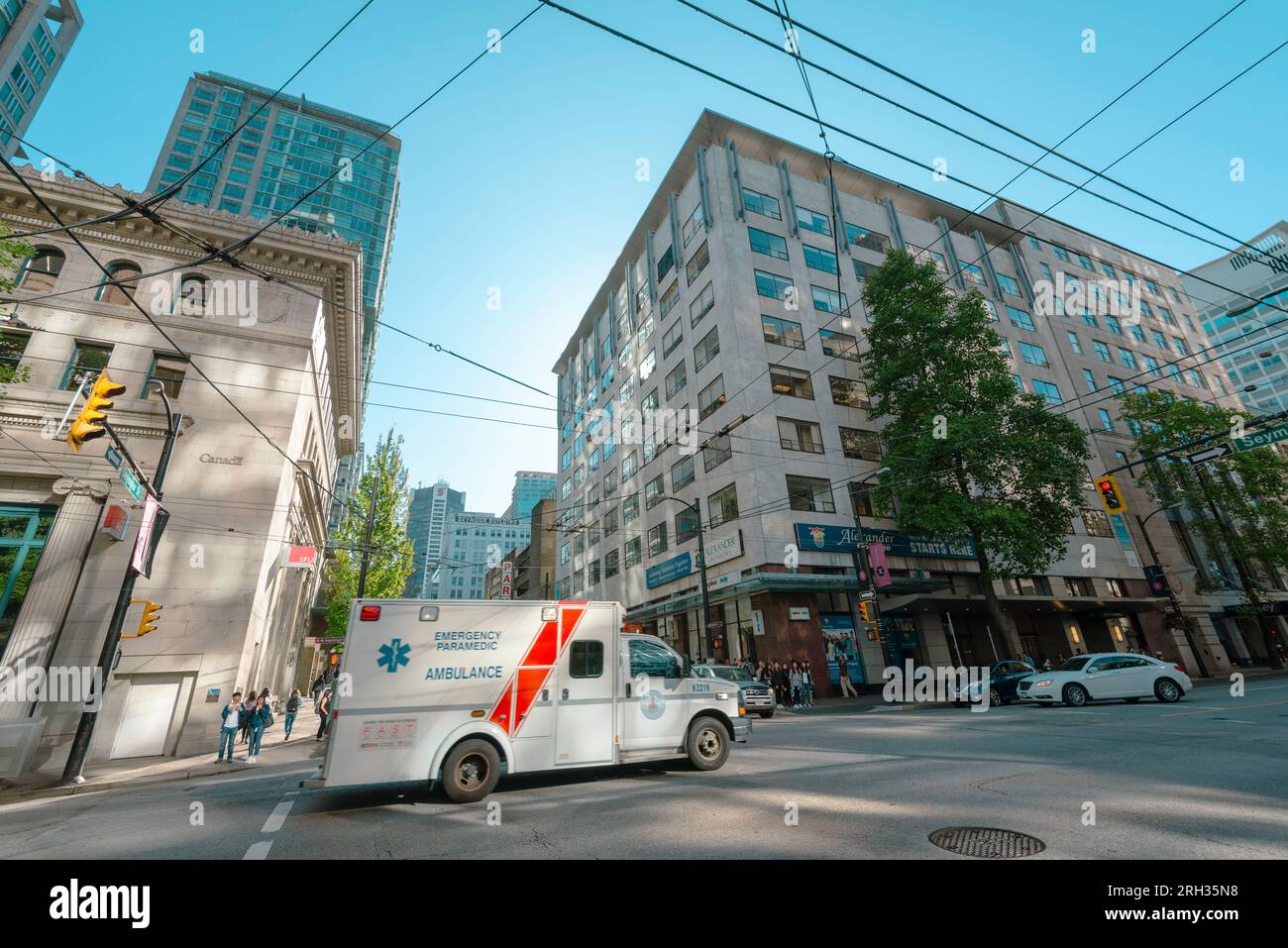 An ambulance drives passed a junction with overhead tram lines in view in Vancouver Canada Stock Photo