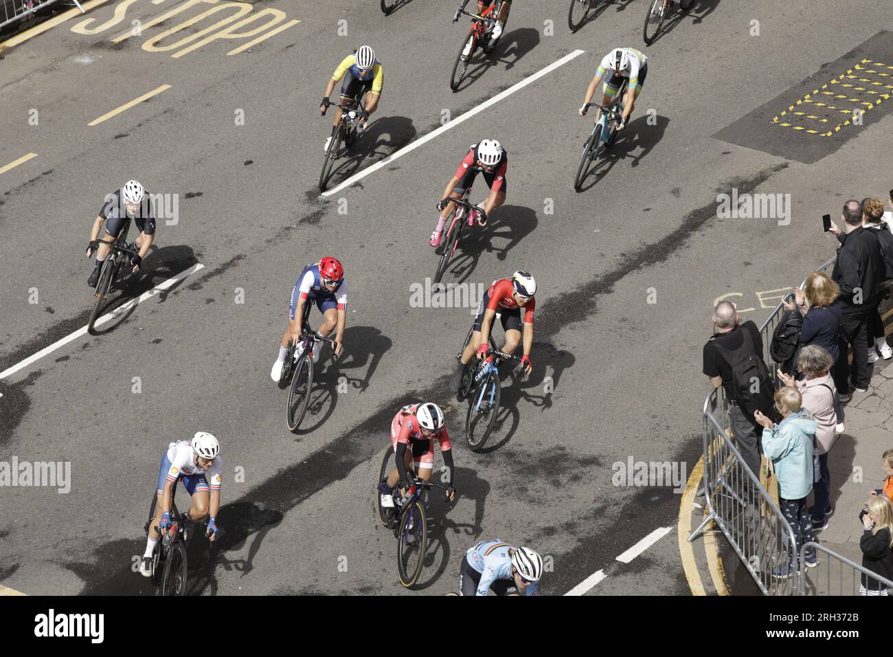 Glasgow, Scotland, UK. 13th August 2023. An overhead view of some of the pro cyclists competing in  The UCI Cycling World Championships  Women Elite Road Race, which started at Loch Lomond and ended with six laps of Glasgow's city streets. Here, a sectionof the peloton, including   Claire Steels of Great Britain and Sze Wing Lee of Hong Kong are turning off Byres Road into Great George Street at the beginning of their first city lap. Credit: Elizabeth Leyden/Alamy Live News Stock Photo
