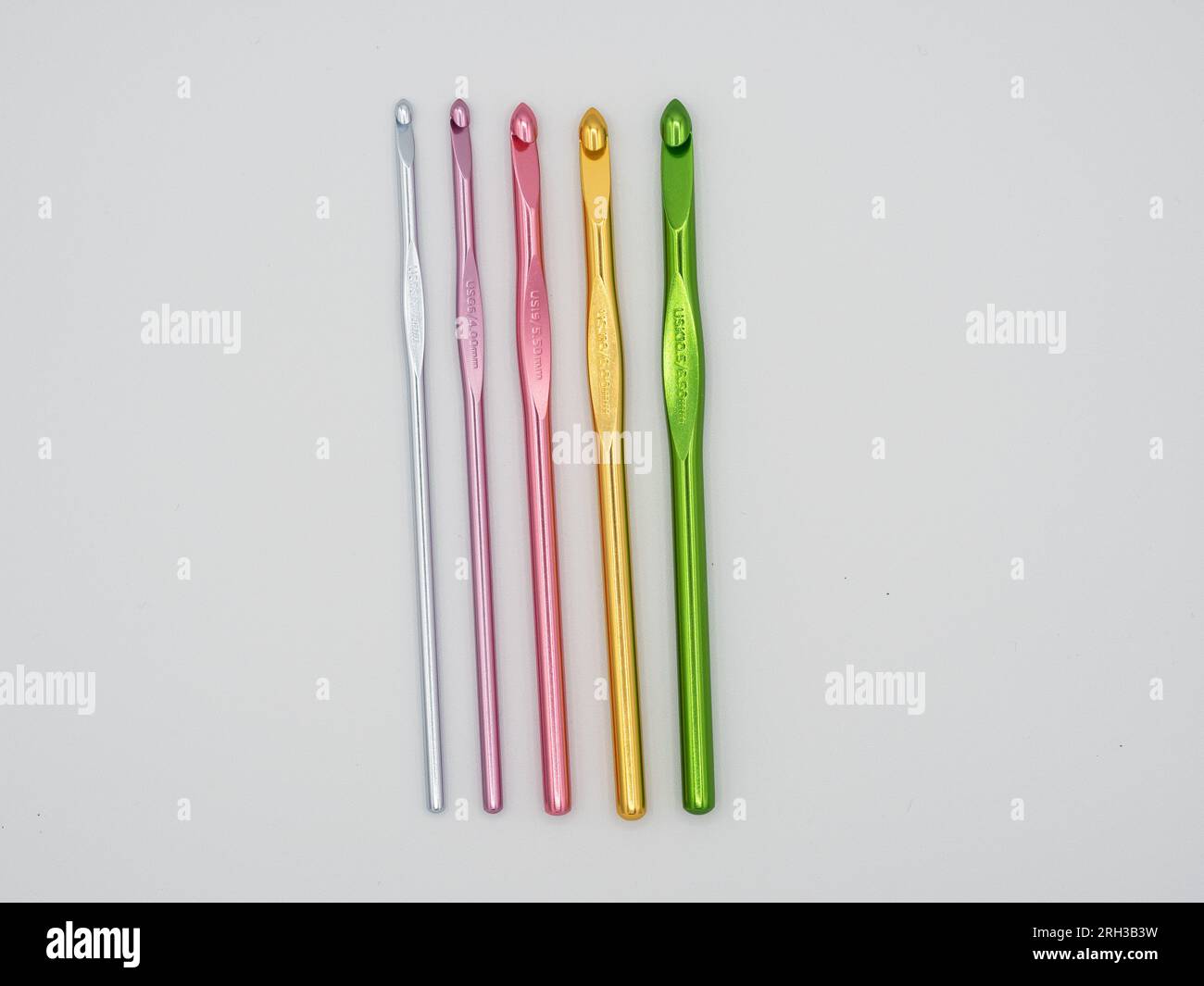 A collection of crochet hooks in different colors is isolated against a white backdrop. Stock Photo