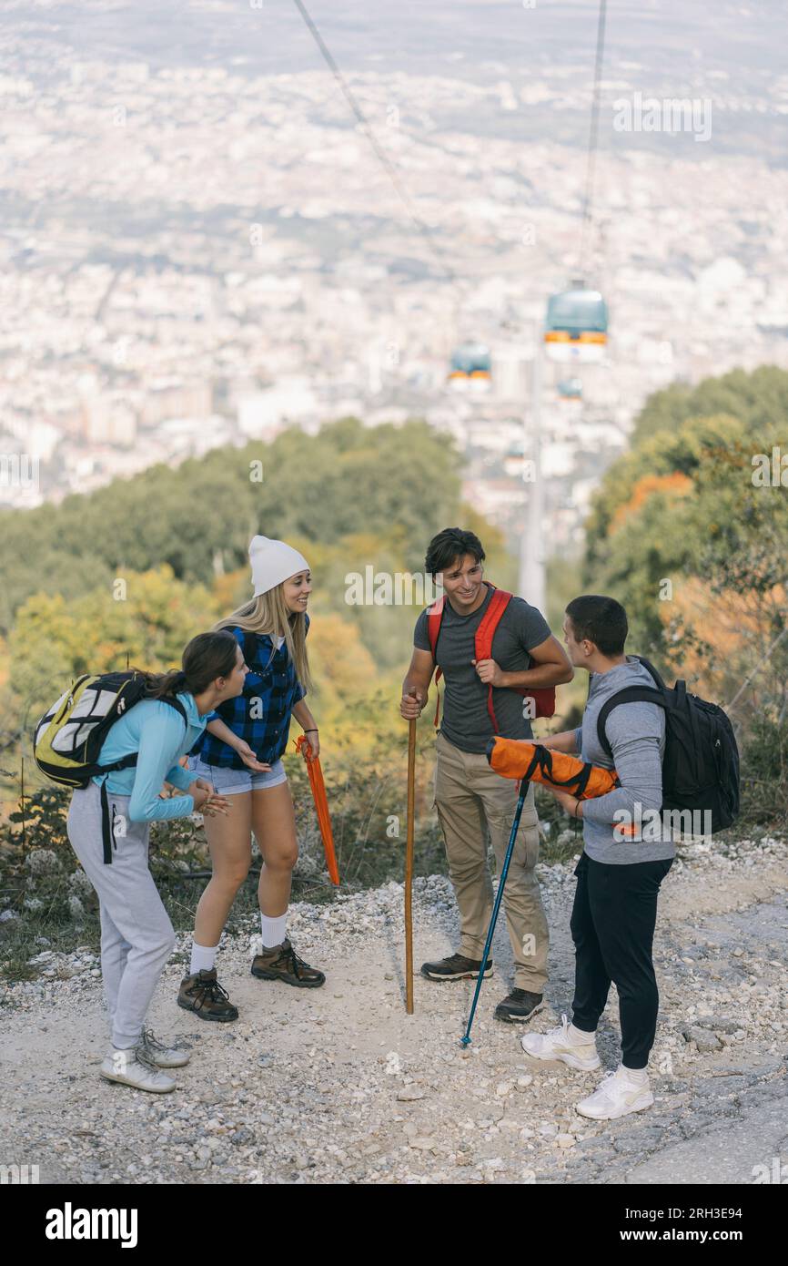 Four sporty friends standing on a dirt road and taking a break. They are having a fun conversation. Panoramic view Stock Photo