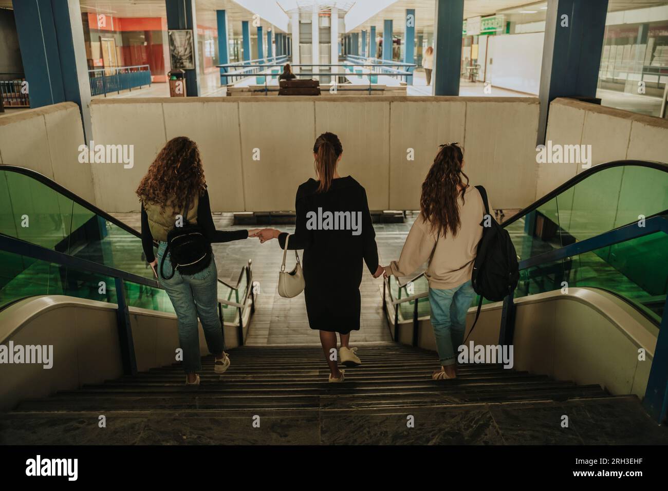 Back view shot of three girls walking downstairs at the shopping mall