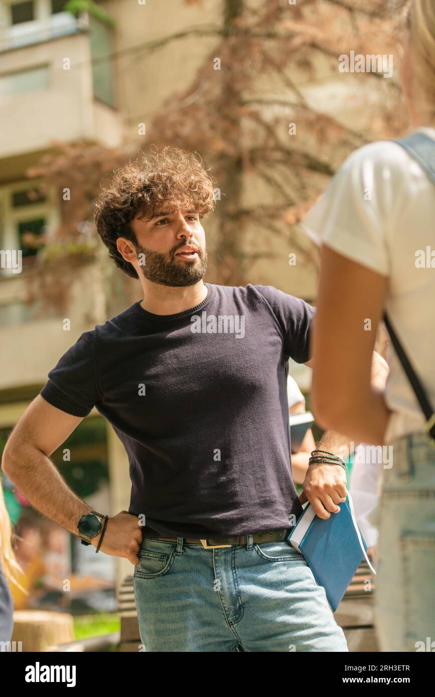 Young and handsome male student talking with his classmate while taking a break from classes Stock Photo