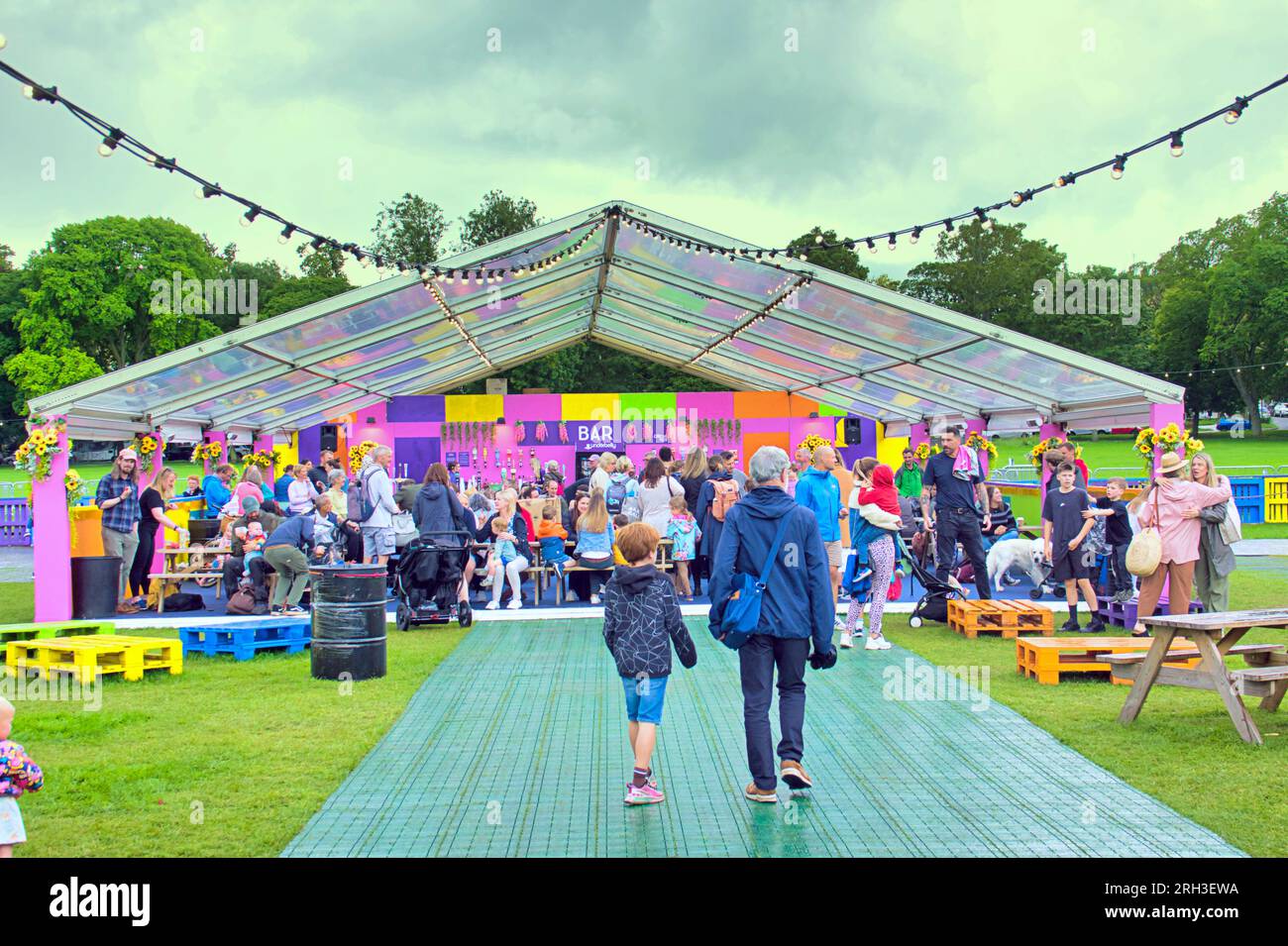 Edinburgh, Scotland, UK. 13h  August, 2023. UK Weather:  Circus hub on the meadows popular bar and food as well as clowns. Warm and wet as tourists infested the streets of the city amongst the street fringe acts with their brollies . Credit Gerard Ferry/Alamy Live News Stock Photo