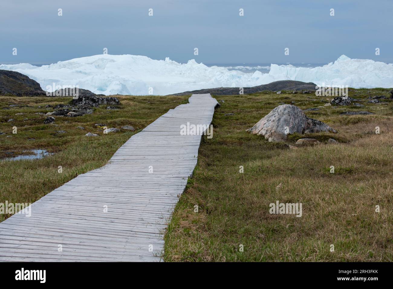 Greenland, Ilulissat, Disko Bay. Wooden walkway leading to Ilulissat Ice Fjord, Sermermiut Trail. UNESCO World Heritage Site. Stock Photo