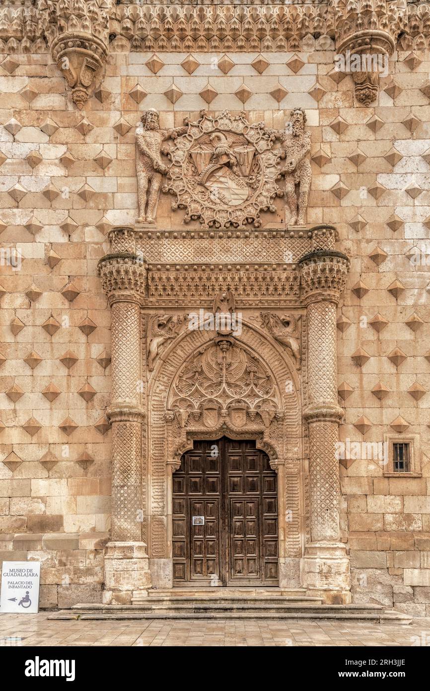 Portal inspired by the Mudejar palaces of the 14th century, door between columns, heraldic lintel, pointed arch and facing figures on the spandrels. Stock Photo