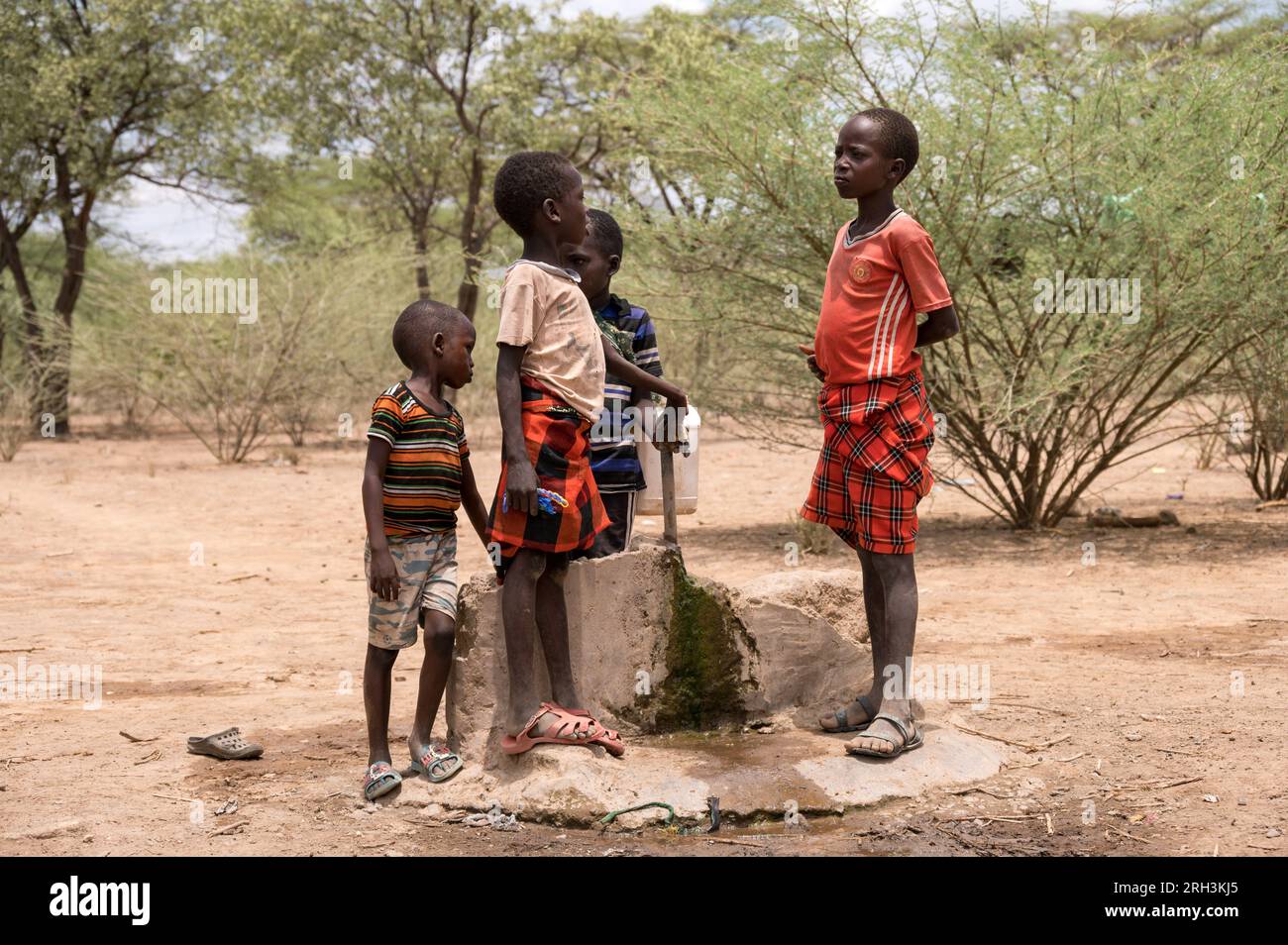Young Kenyan boys stands by a water tap sourcing fresh water from a nearby bore hole, Baringo County, Kenya Stock Photo