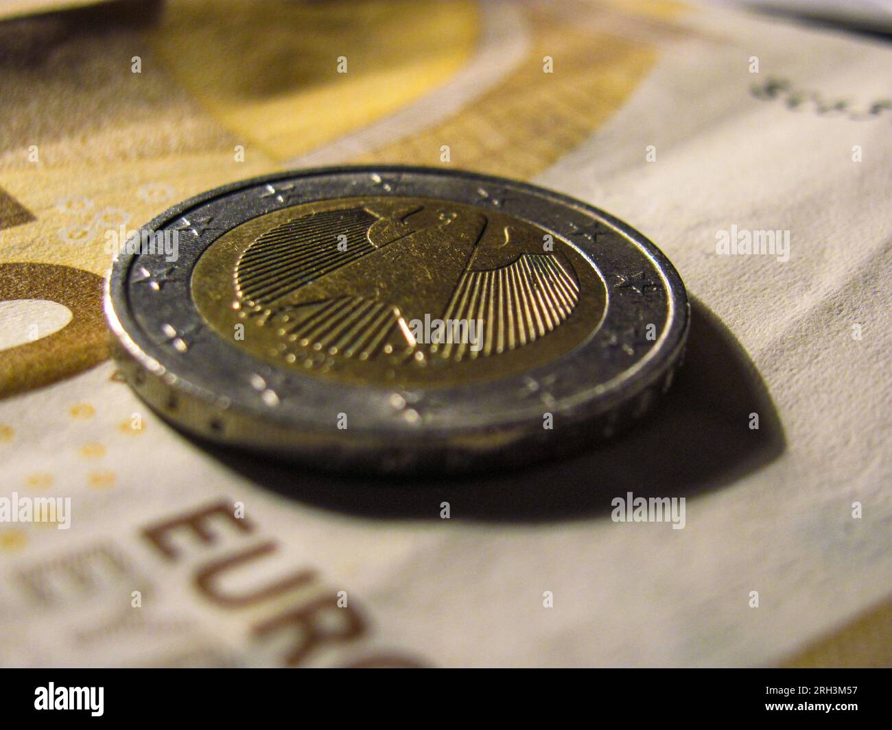 Currency Contrast: Euro Coin Rests Upon a €50 Banknote Stock Photo