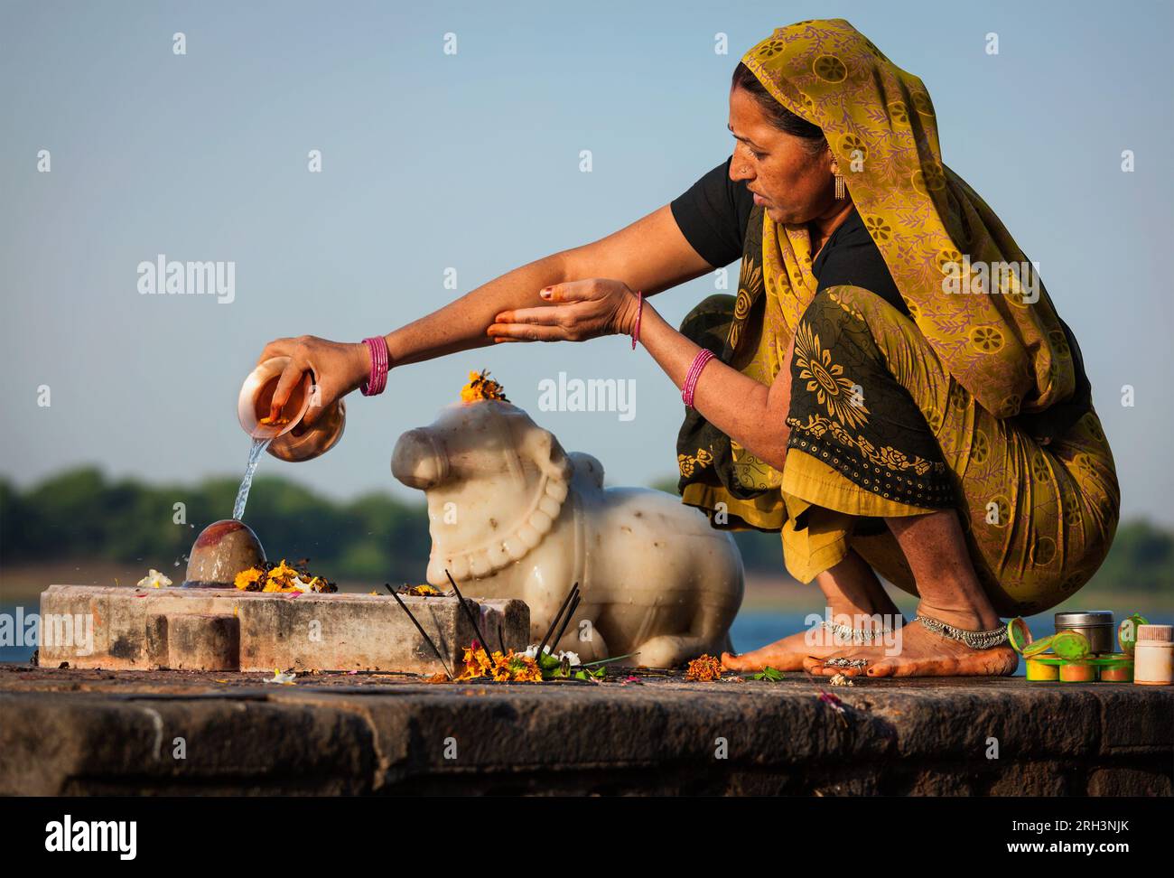 Indian woman performs morning pooja on holy river Narmada ghats Stock Photo