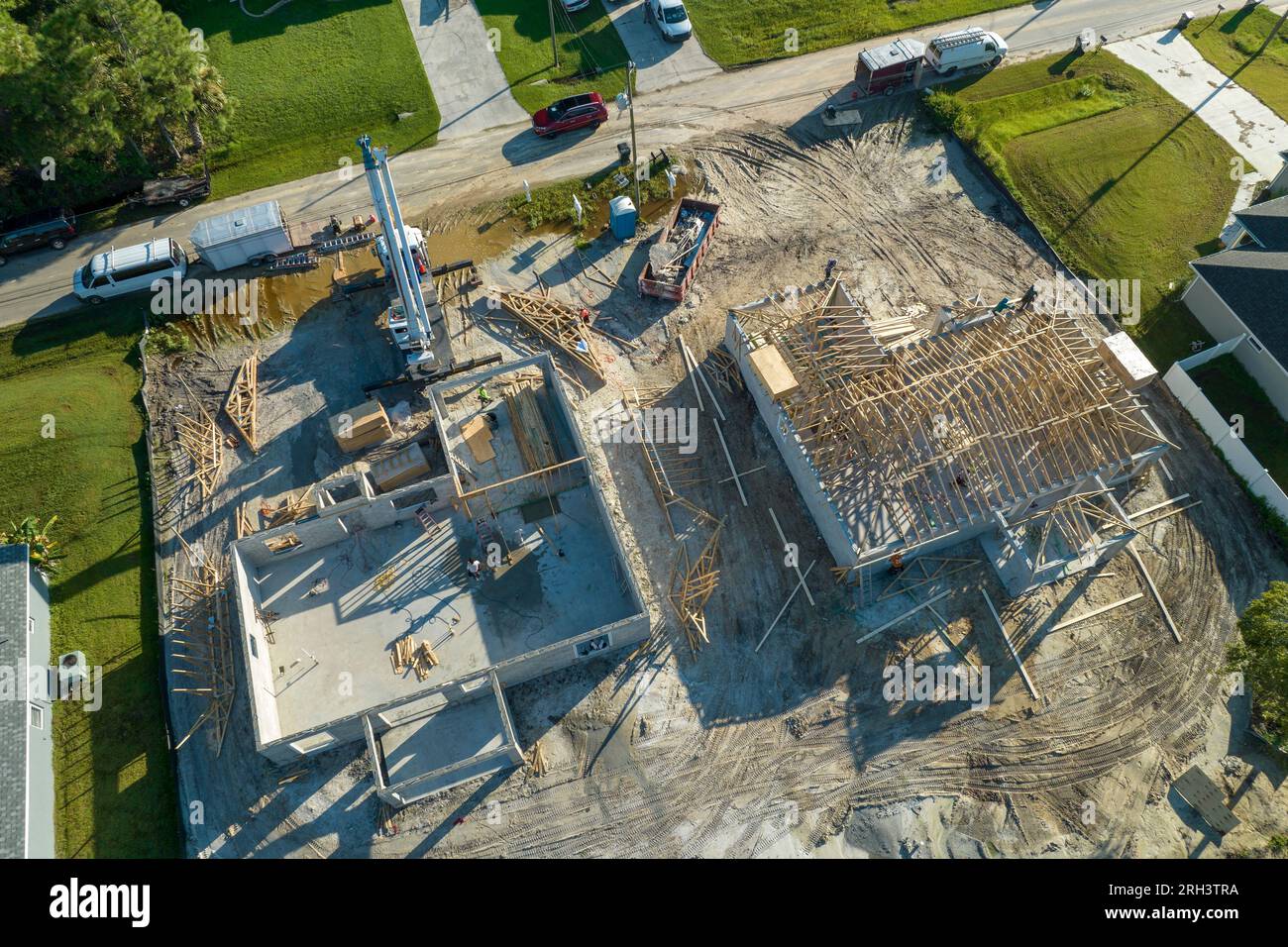 Professional builders and crane truck working on roof construction of unfinished suburban home with wooden frame structure in Florida rural area Stock Photo