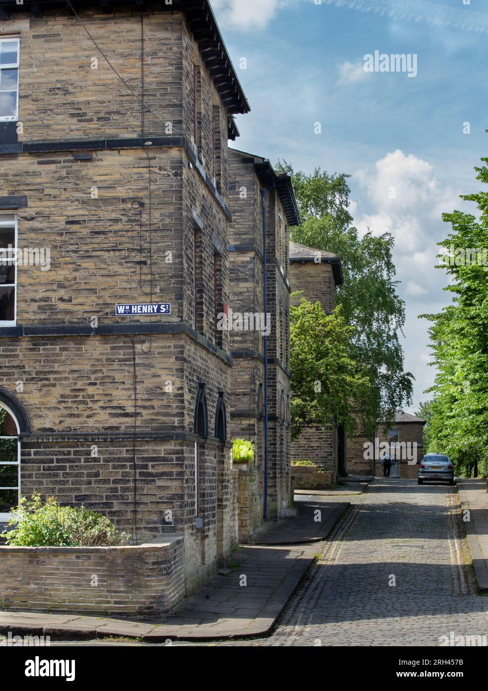 The corner of William Henry Street and cobbled  Albert Terrace in Saltaire, Yorkshire showing mill workers cottages from nearby Salts Mill. Stock Photo