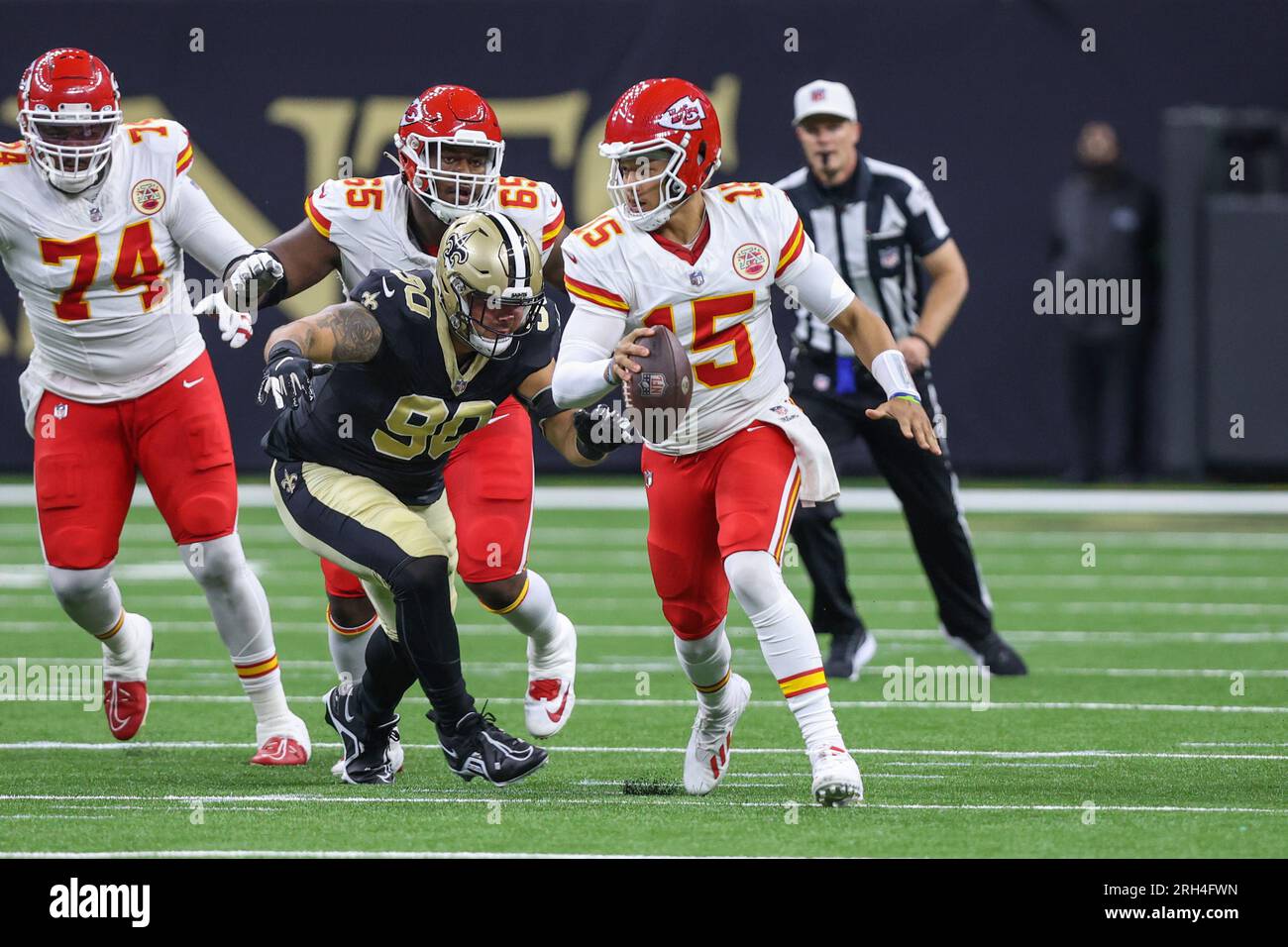 New Orleans, USA. August 13, 2023: Kansas City quarterback Patrick Mahomes  (15) runs out of the pocket as Saints defensive lineman Bryan Bresee (90)  give chase during NFL pre-season game action between