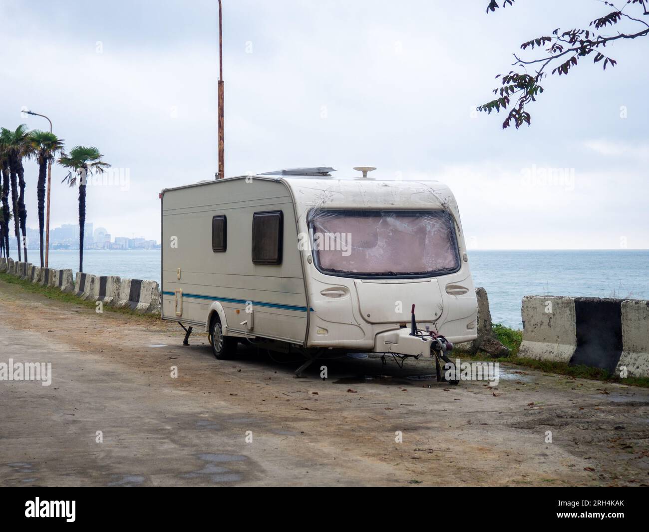 Old trailer in the parking lot. Vacationers savages on the sea. Your home on wheels. Stock Photo