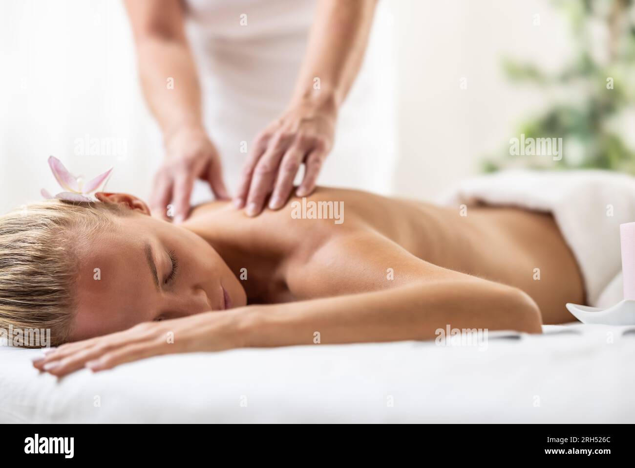 Beatiful woman is enjoying relaxing back massage in cosmetology spa centre. Stock Photo