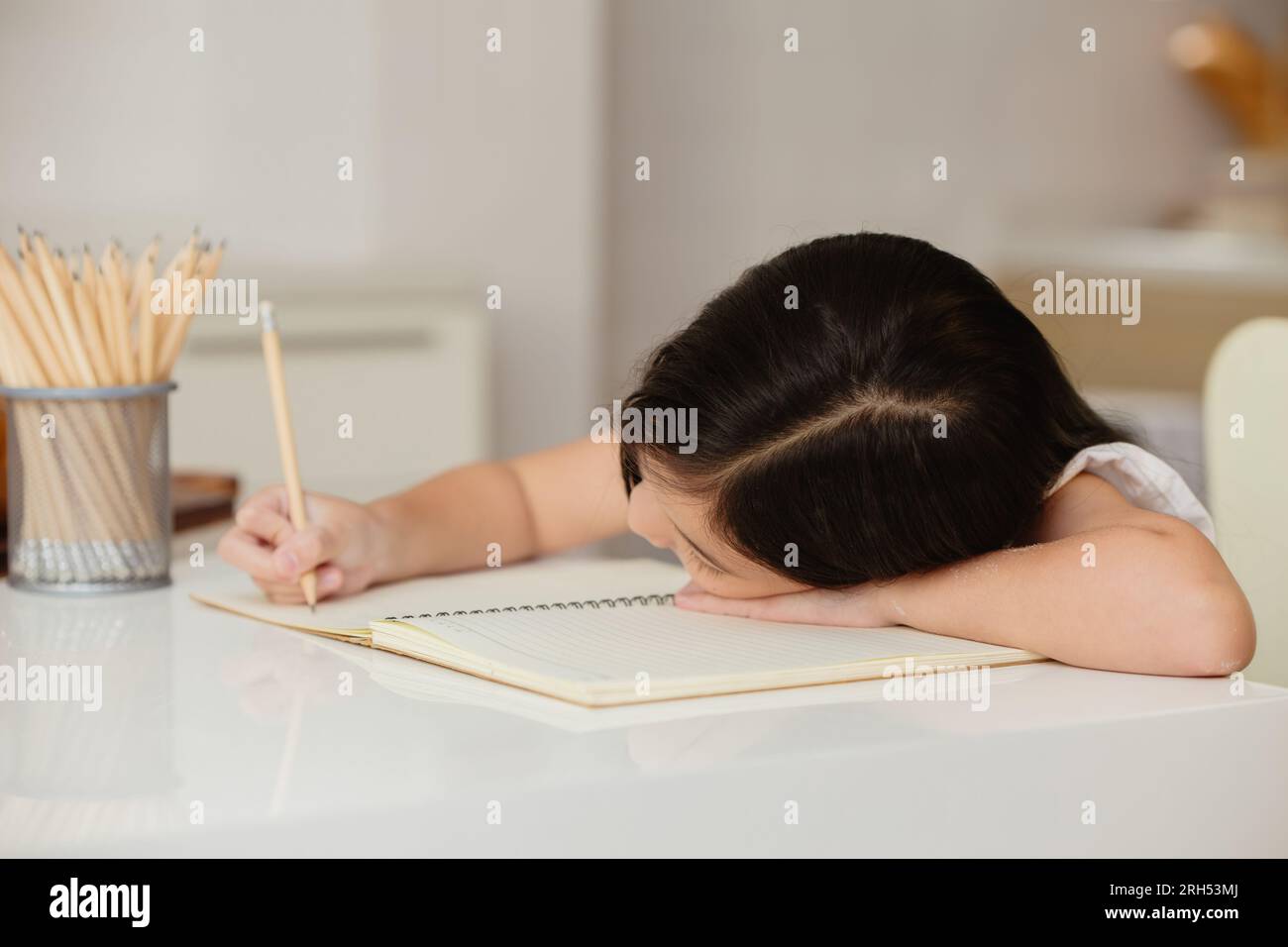 child girl lazy education at home feel boring sitting head down doing homework Stock Photo