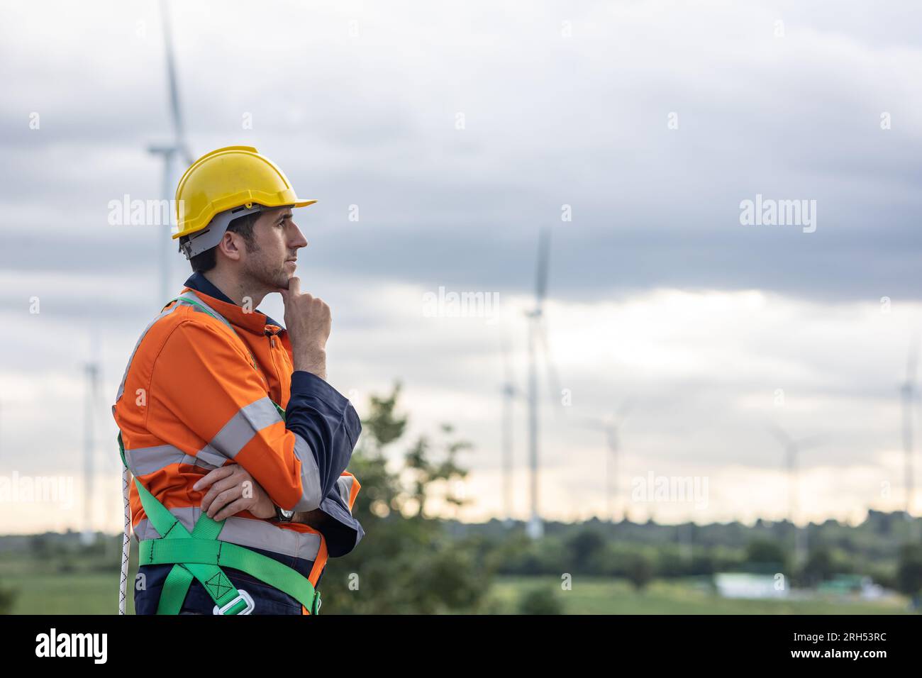 Professional Engineer male worker standing thinking hand at chin at wind turbine field working Stock Photo