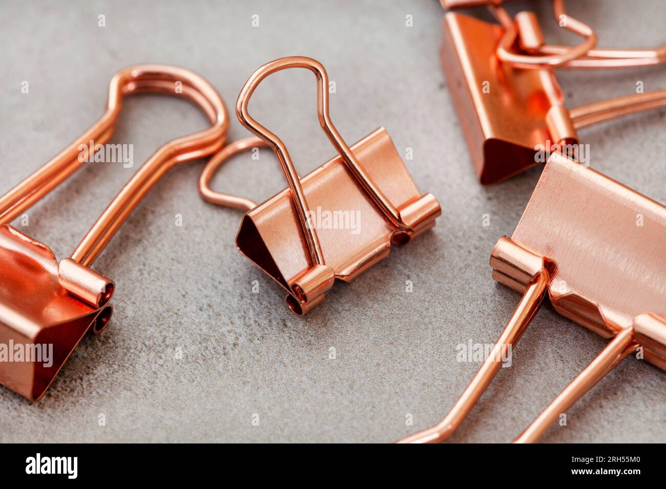 rose gold copper colored paper clips on mottled gray Stock Photo
