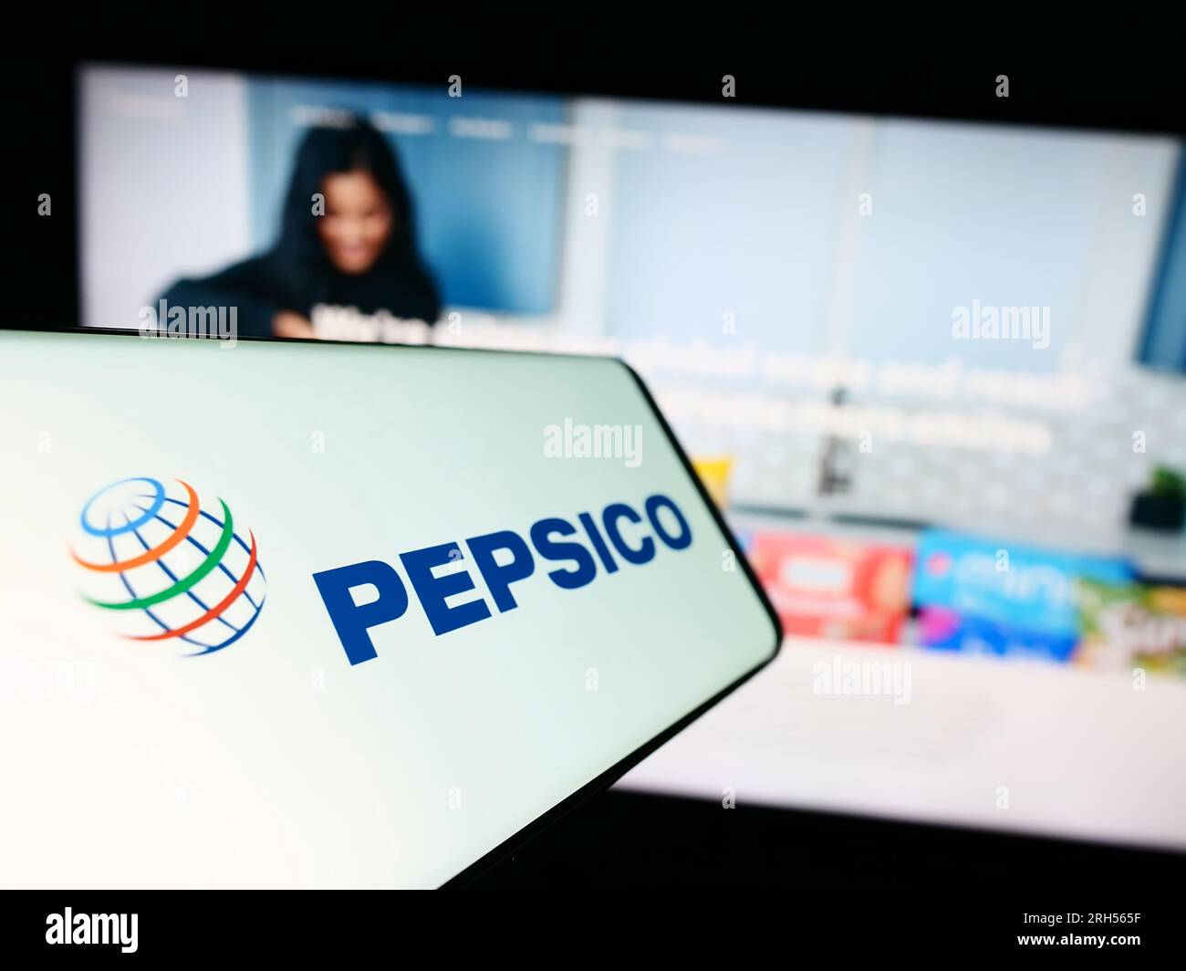 Mobile phone with logo of American beverage and snack company PepsiCo Inc. on screen in front of website. Focus on center-left of phone display. Stock Photo