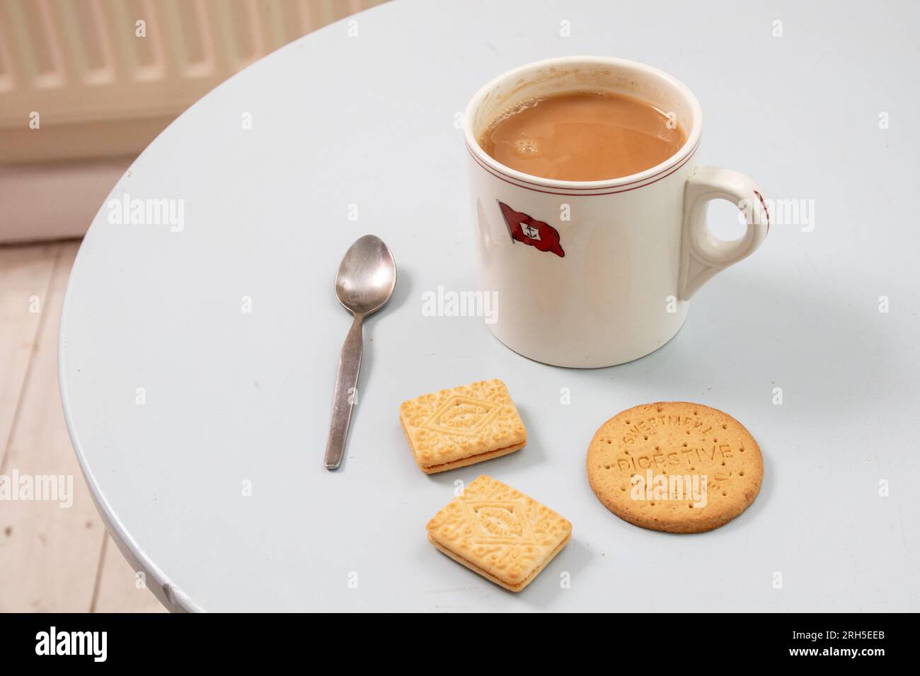 A mug of strong tea and three biscuits waiting for a very British moment of refreshment Stock Photo