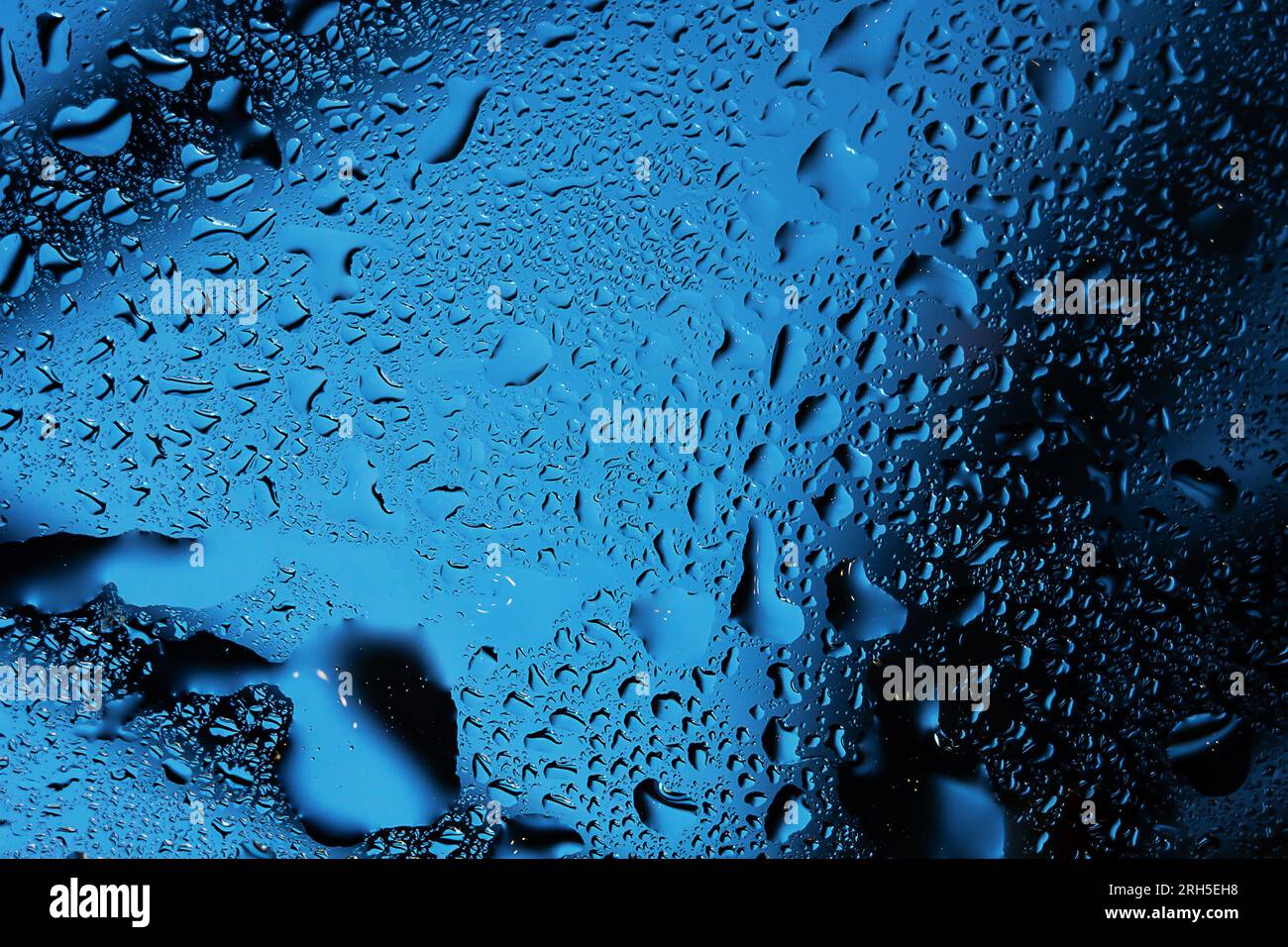 Raindrops on a clear window create a wet and rainy background. Stock Photo