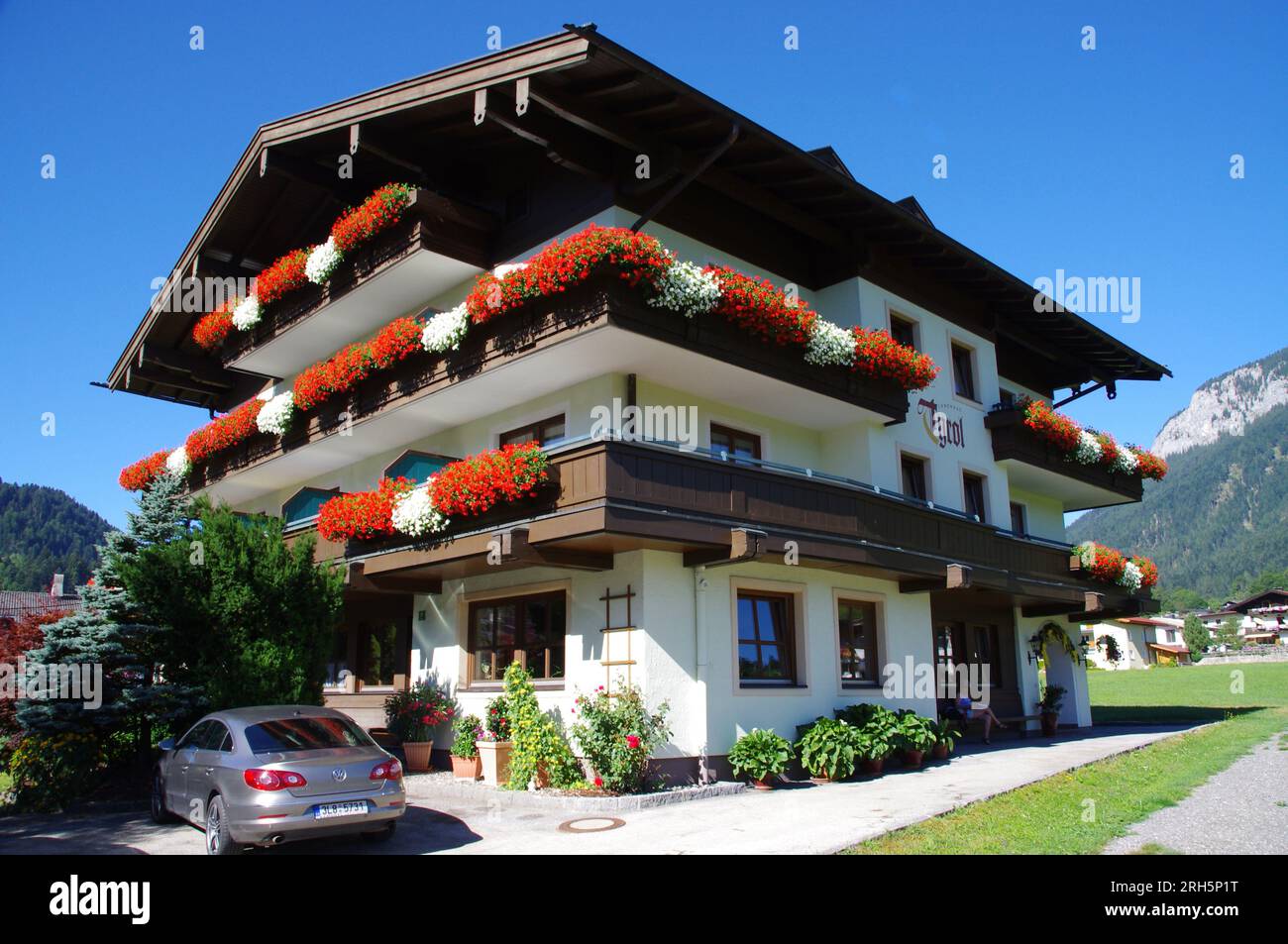 Söll, Austria, Typical Austrian Wooden buuilding with red and white flower baskets. Hotel Tyrol, Söll. Stock Photo
