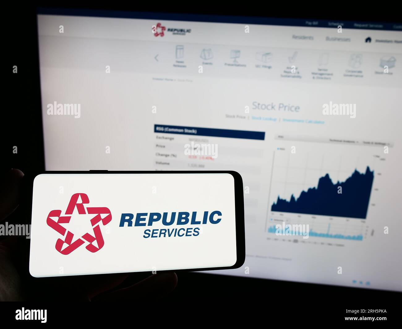 Person holding mobile phone with logo of US waste disposal company Republic Services Inc. on screen in front of web page. Focus on phone display. Stock Photo