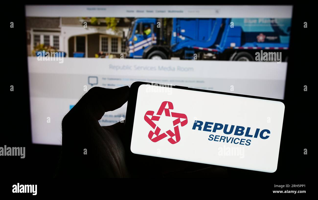 Person holding smartphone with logo of US waste disposal company Republic Services Inc. on screen in front of website. Focus on phone display. Stock Photo