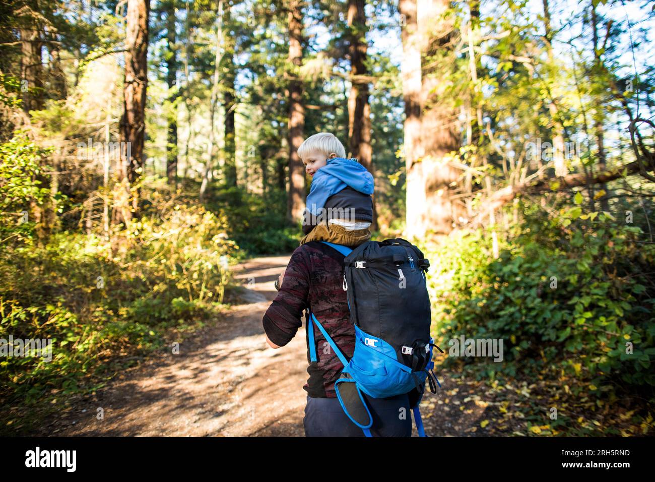 Rear view of father carry his son on his back while hiking outdoors Stock Photo