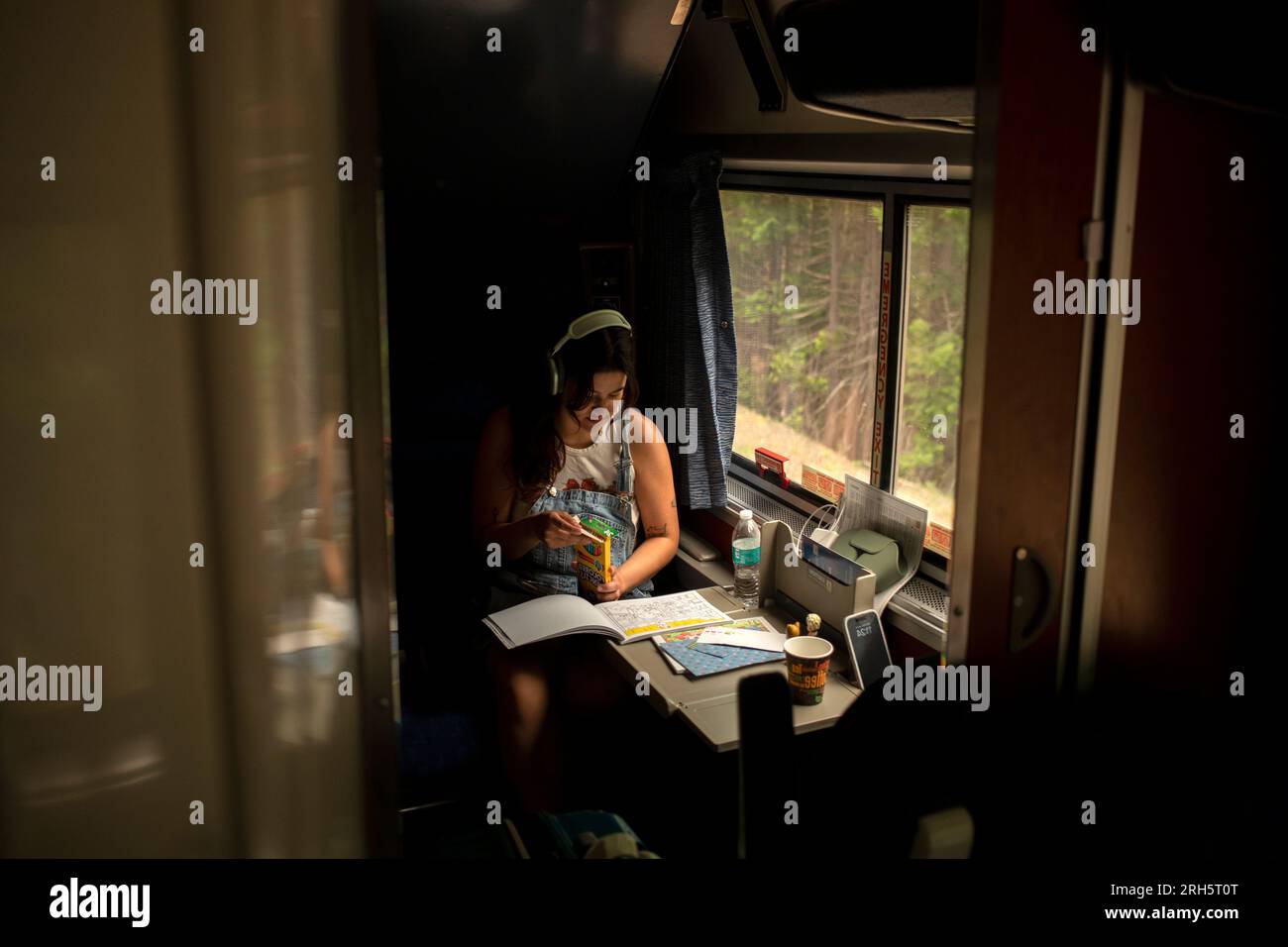 Young woman riding passenger train with coloring book Stock Photo